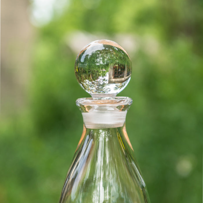 Clear glass decanter with spherical stopper and frosted band around the neck.