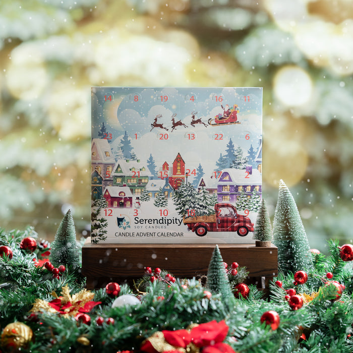 Serendipity Candle Advent Calendar surrounded by Christmas decorations with a snowy village scene.