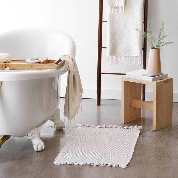 Bath mat in front of claw foot tub and ladder, ivory