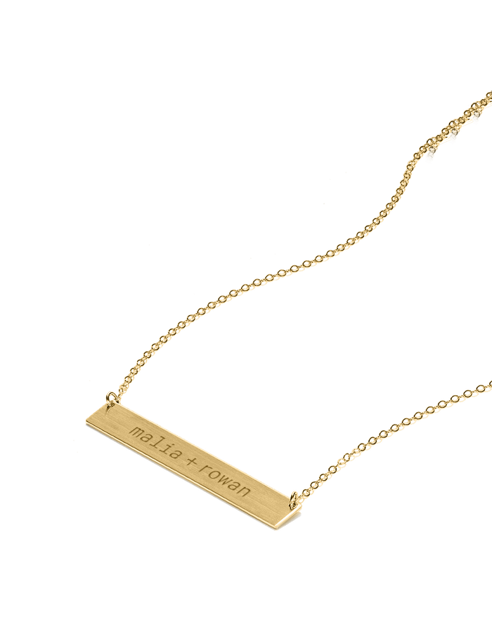 Gold bar necklace with custom engraved text, angled view