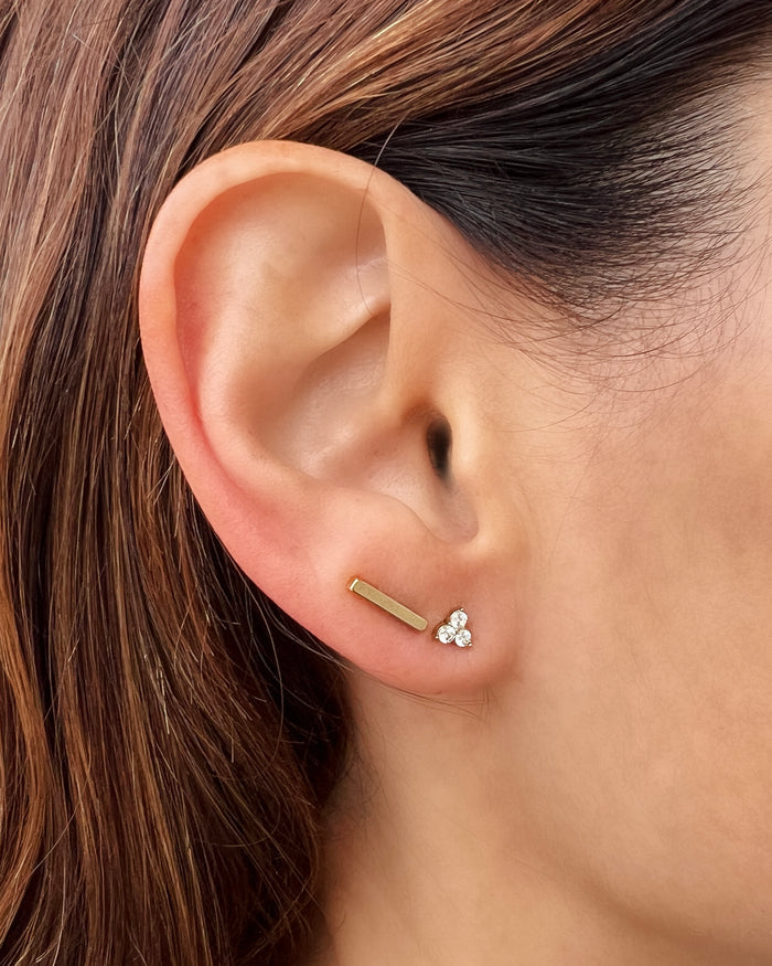 Set of small gold stud earrings worn on an ear