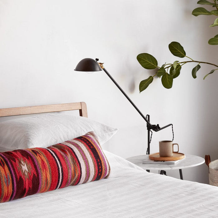 Geometric and striped oversized lumbar pillow styled on bed with side table, multicolor