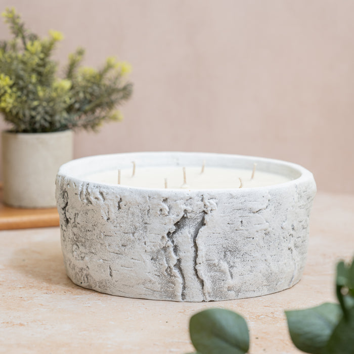 Concrete candle container surrounded by green decor