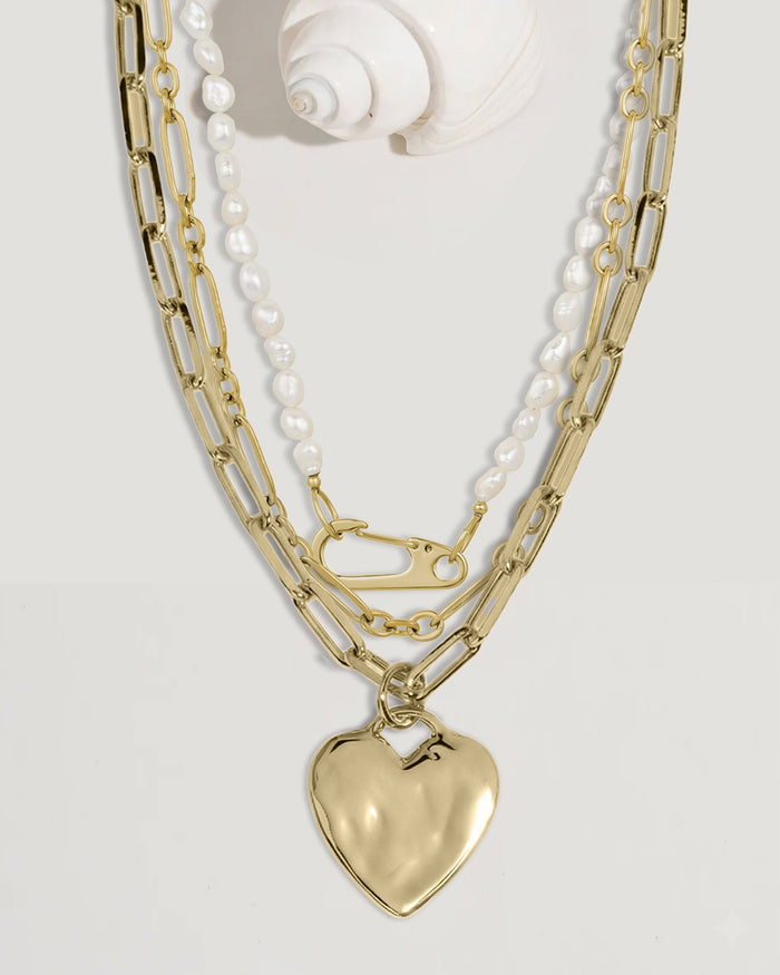 Gold chain necklace set with heart lock and pearl charms, flat lay