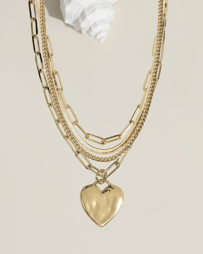 Set of chunky gold necklaces with heart charms, flat lay