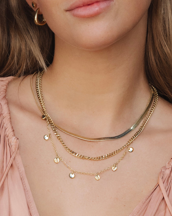 Woman wearing layered necklaces with a coin pendant