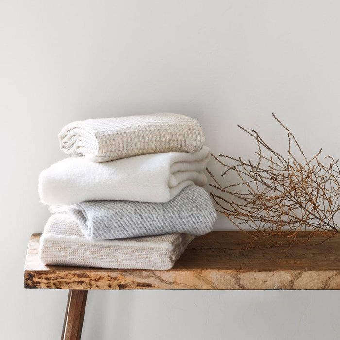 Stack of Alpaca and Wool Throw Blankets on a Bench, sand