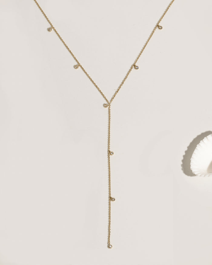 Gold lariat necklace with multiple bezel-set crystal charm drops on fine chain