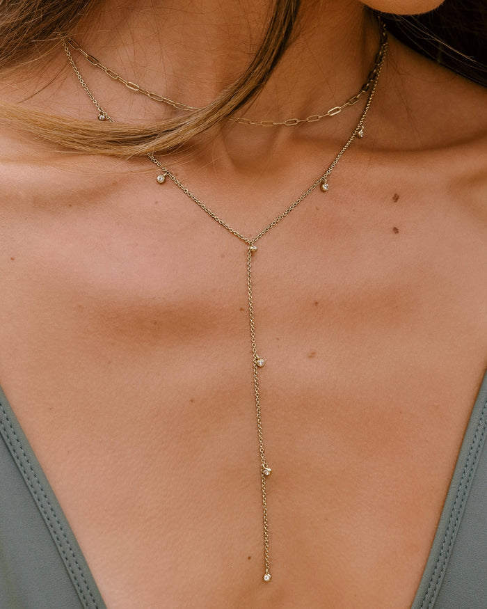Gold lariat necklace with multiple bezel-set crystal charm drops on fine chain