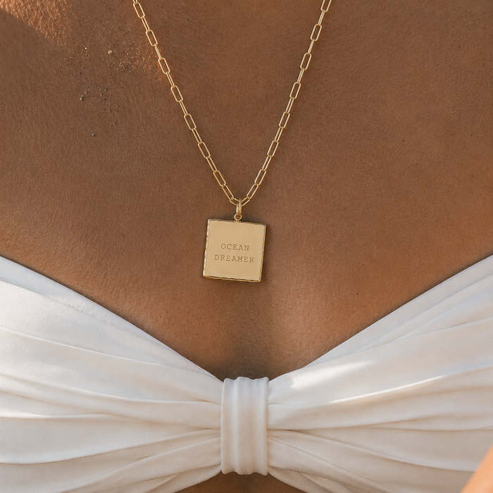 Gold square pendant necklace engraved with custom text worn on back