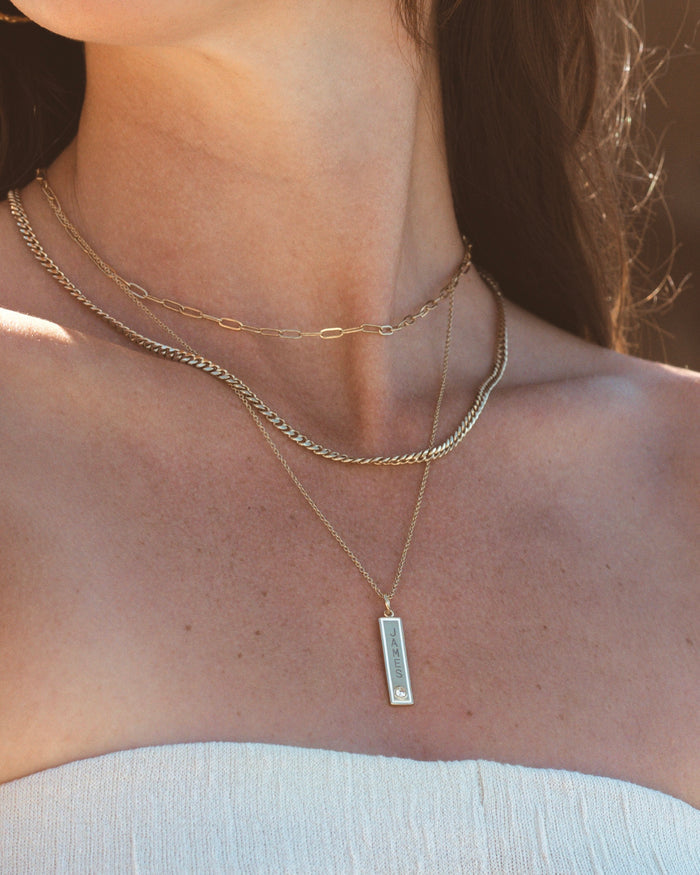 Model wearing layered necklaces with vertical bar pendant