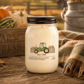 Jar candle with 'Fall Farm' label on a wooden surface with pumpkins and a plaid blanket in the background.