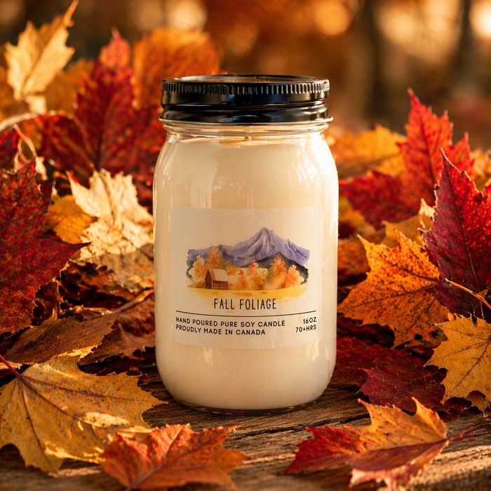 Jar candle labeled 'Fall Foliage' surrounded by autumn leaves