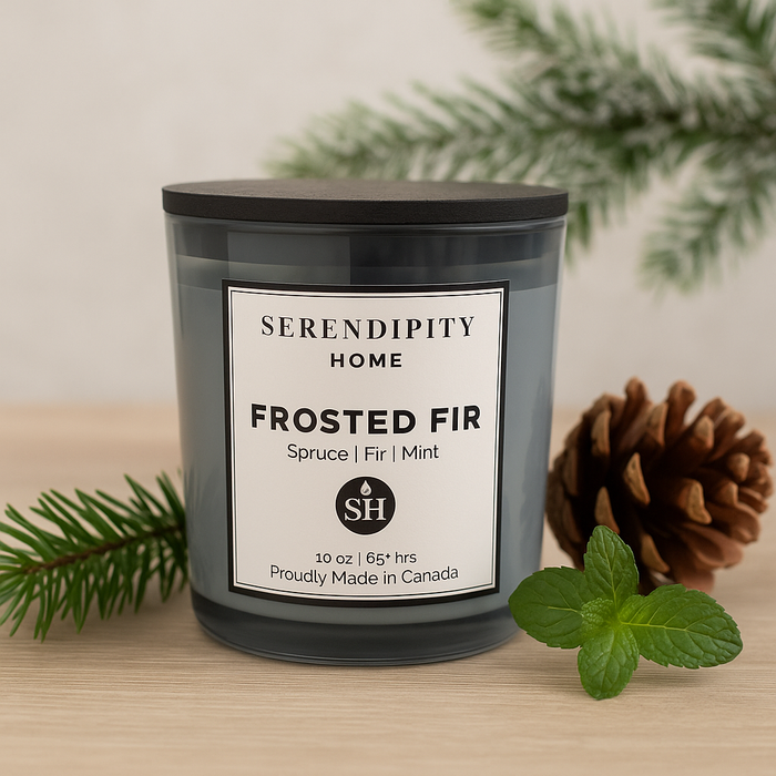 Candle labeled 'Frosted Fir' from Serendipity Home with decorative elements on a wooden surface.