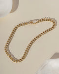 Gold chunky curb chain bracelet on cream surface with white shell