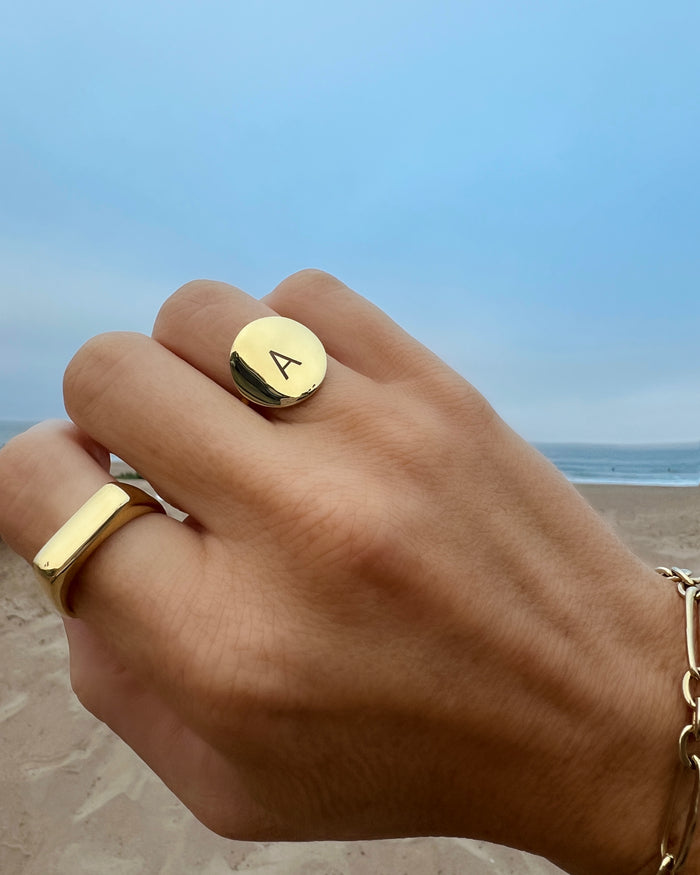 Hand at the beach wearing a gold ring