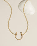 Gold horseshoe pendant necklace on a delicate chain