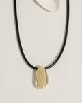 Gold necklace with a dark pendant worn on a model