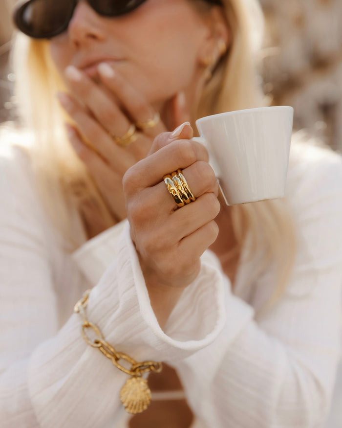 Gold cigar-band ring worn on a hand