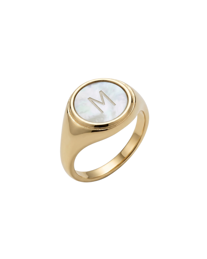 Gold signet ring with mother-of-pearl initial disc, close-up view