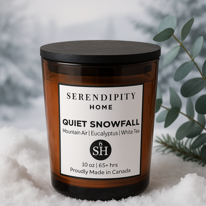 A Serendipity Home scented candle labeled 'Quiet Snowfall', with Mountain Air, Eucalyptus and White Tea notes