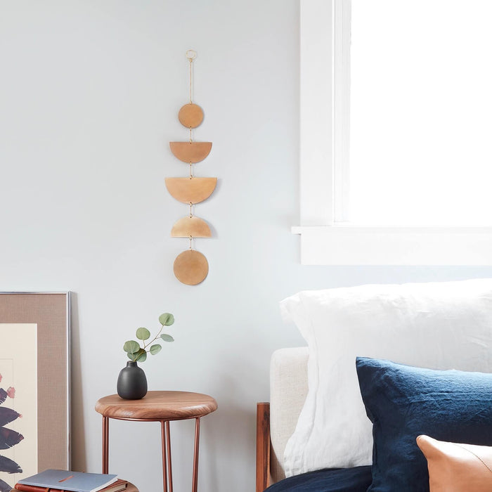 Geometric brass wall hanging next to bed, brass