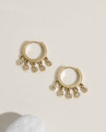 Gold huggie hoop earrings with bezel-set crystal drops along the lower half of the hoop