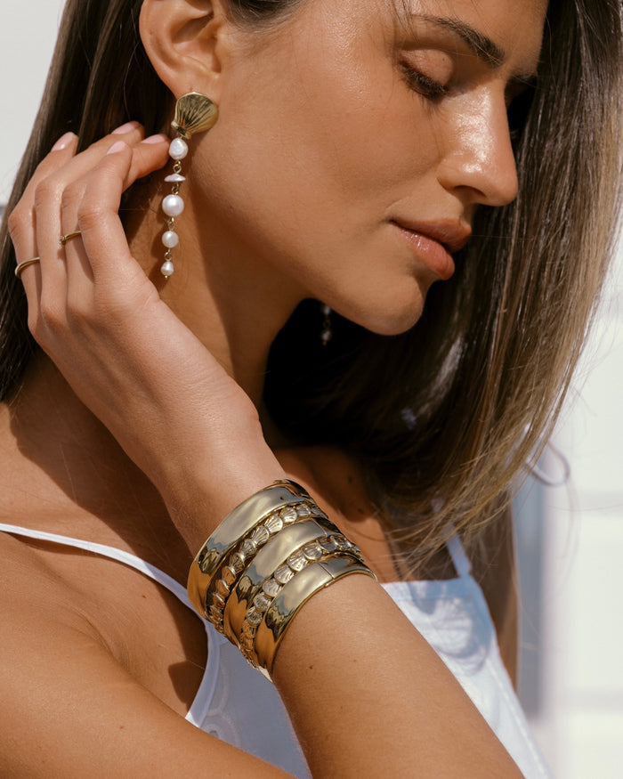 Gold beaded bracelet with tiny white shell charm pendant, detail view