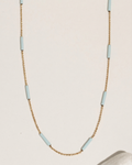 Gold chain necklace with a blue accent, flat lay