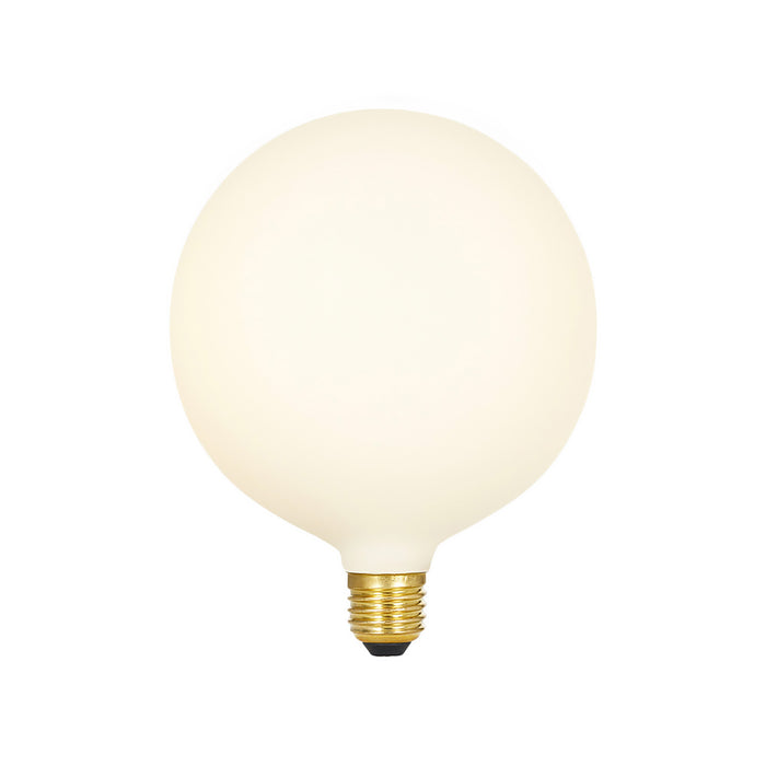 Spherical matte cream porcelain LED bulb with brass base and black contact point.