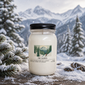 Candle in a mason jar with a mountain-themed label against a snowy mountain backdrop