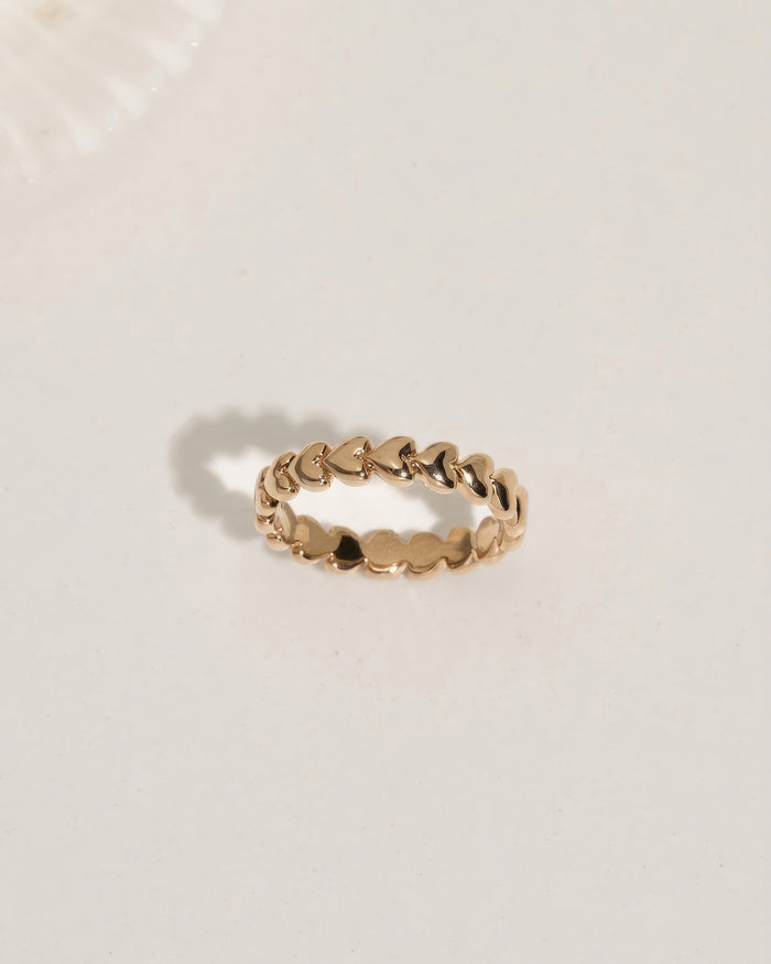 Rose gold stacking ring with a small heart detail, flat lay