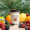 Serendipity candle with tropical berry scent, surrounded by fruit decorated background