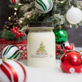 Serendipity "Under the Tree" scented candle, in front of a decorated christmas tree