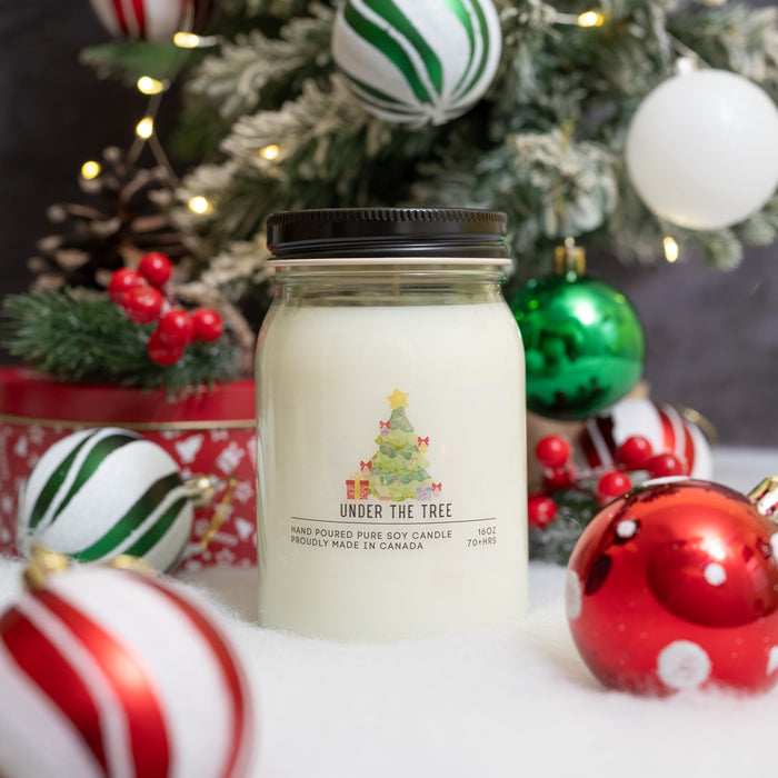 Serendipity "Under the Tree" scented candle, in front of a decorated christmas tree
